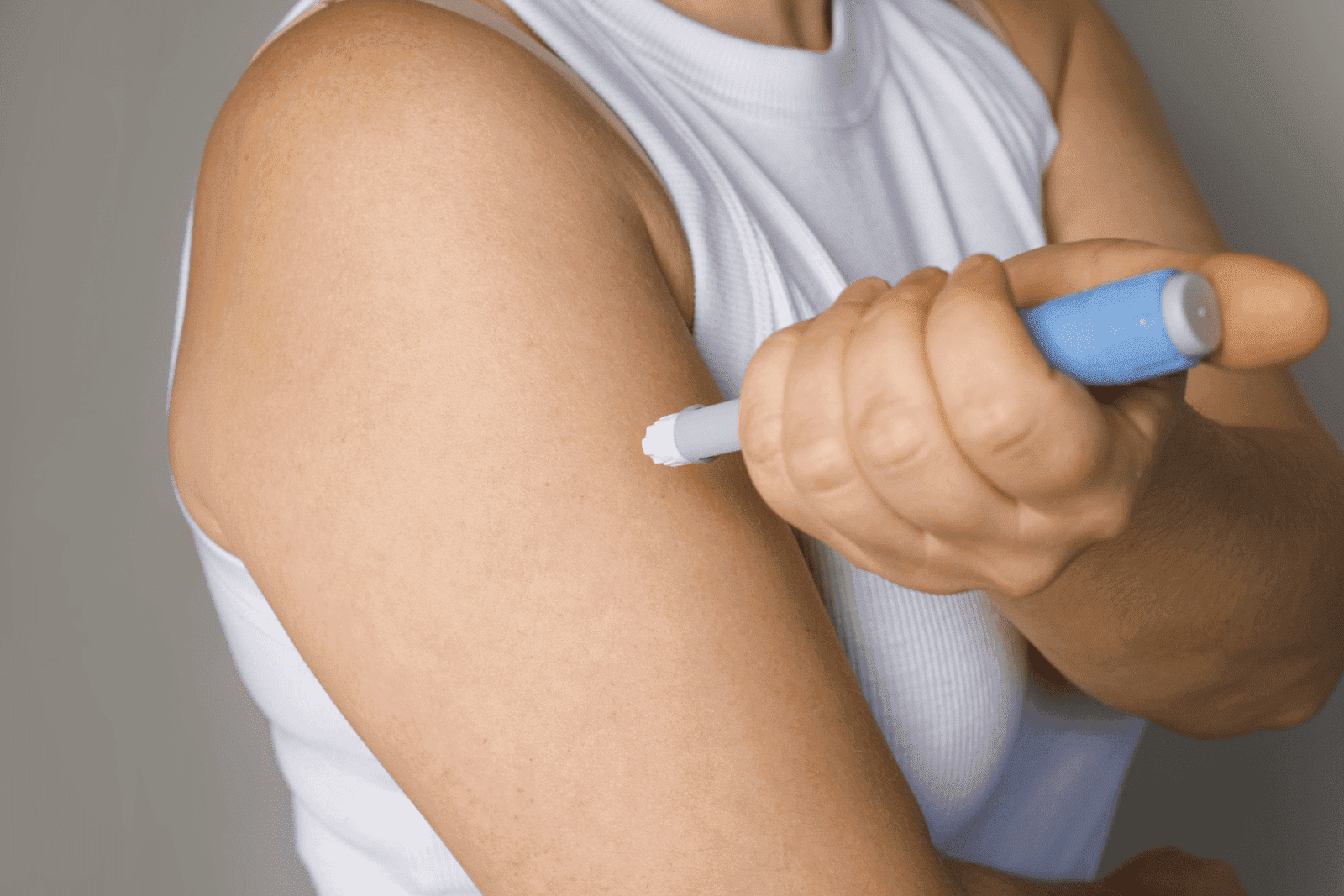 Person administering an injection into the upper arm with an insulin pen