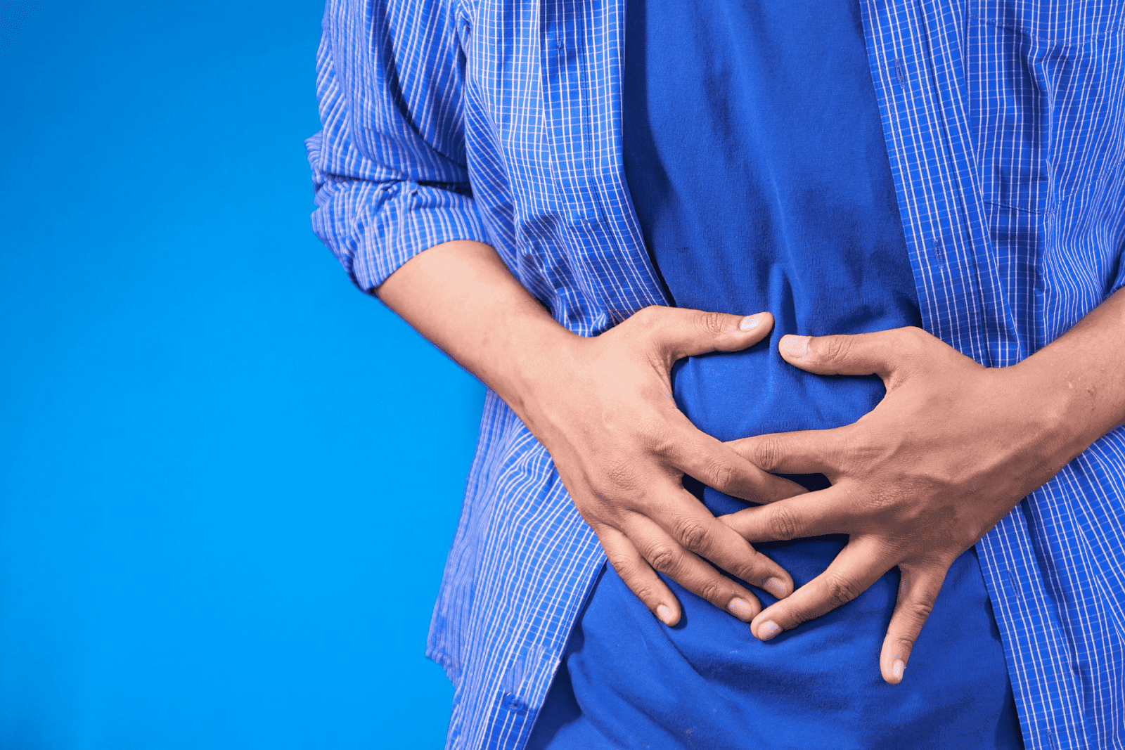 Person clutching their abdomen, indicating stomach pain or discomfort.
