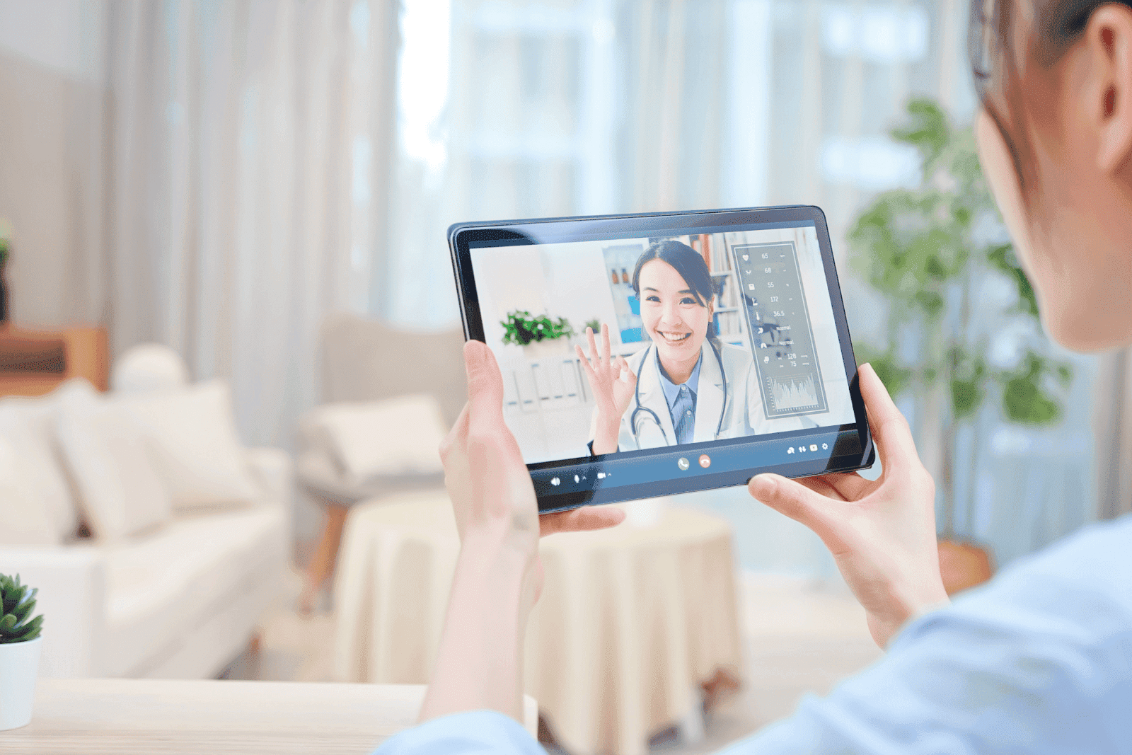 Person having an online video consultation with a smiling doctor on a tablet.
