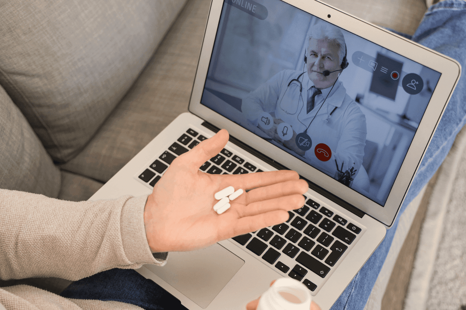 Person holding pills while having an online video consultation with a doctor on a laptop