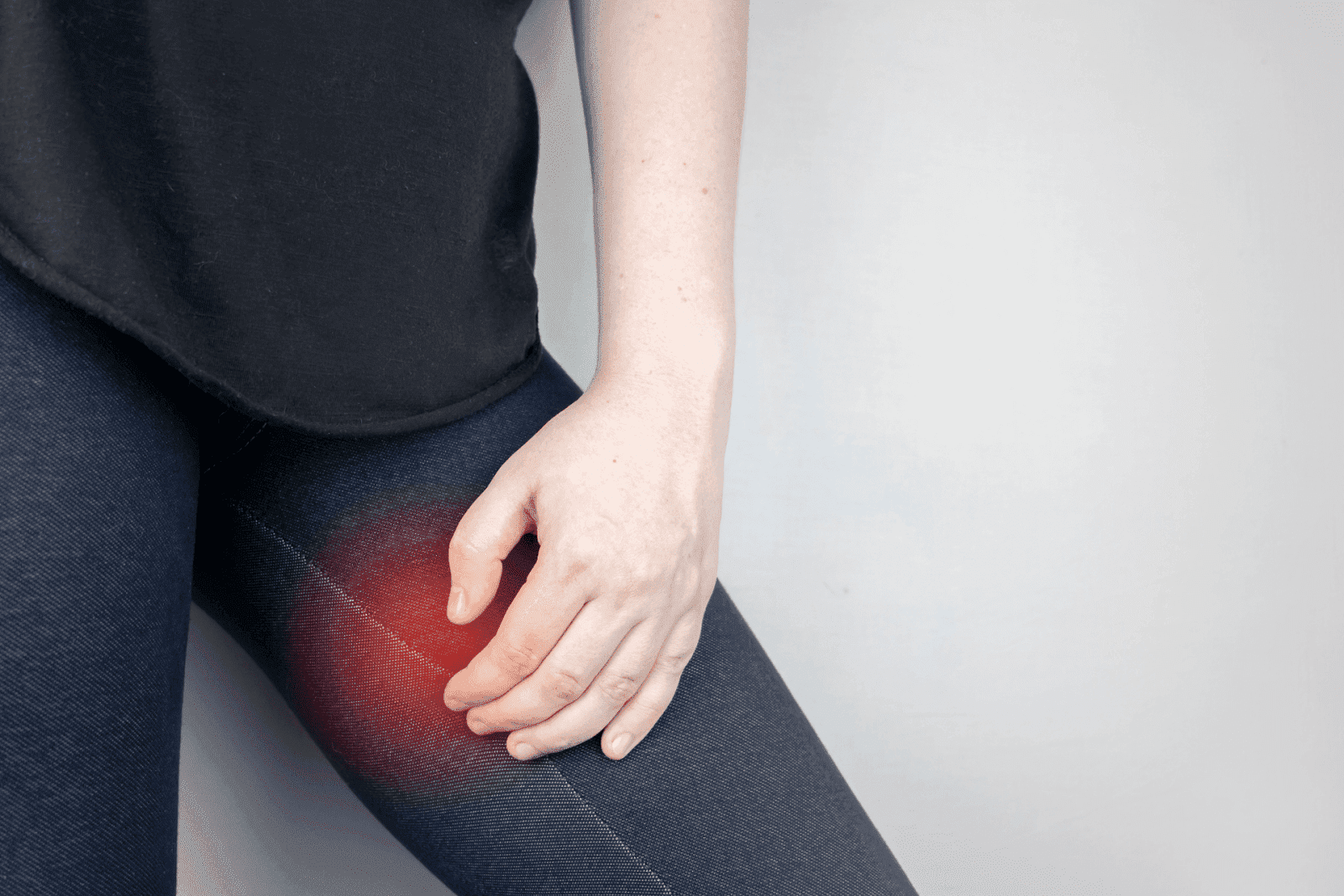 Person holding their thigh with red area indicating pain.