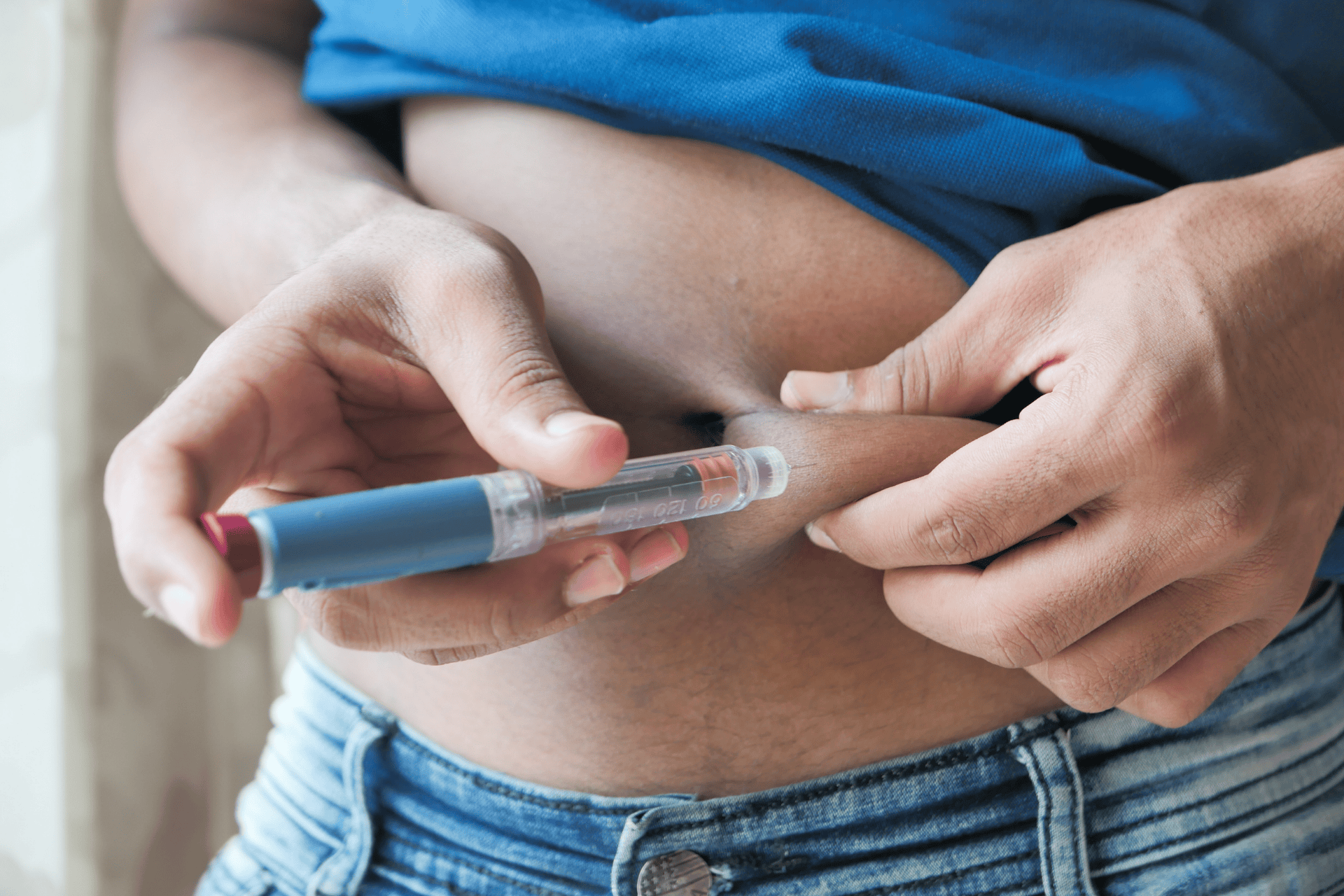 Person injecting medication into their abdomen with an insulin pen