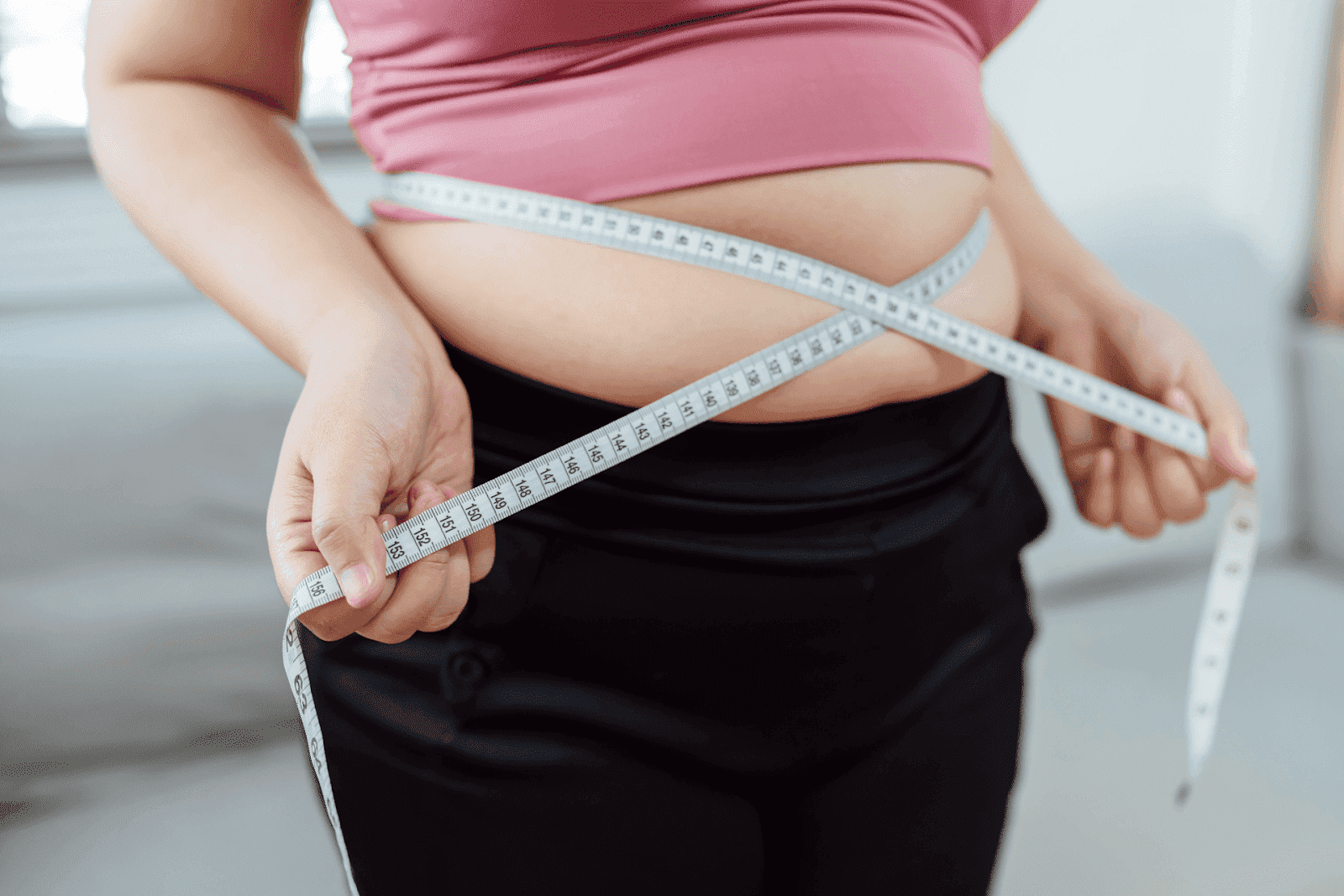 Person measuring their waist with a tape measure