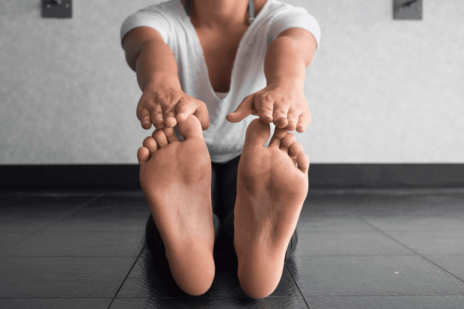 Person stretching forward while seated, reaching for their toes with both hands.