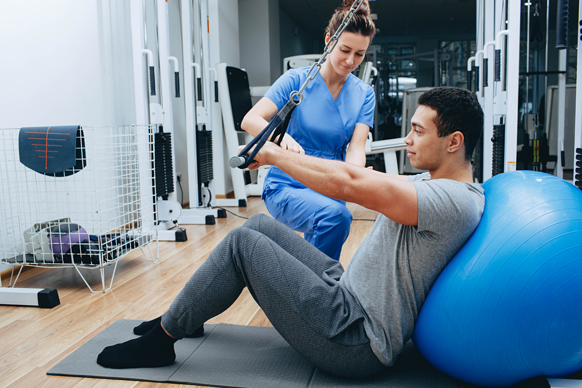 Physical therapist assisting a man with a resistance band exercise on a stability ball
