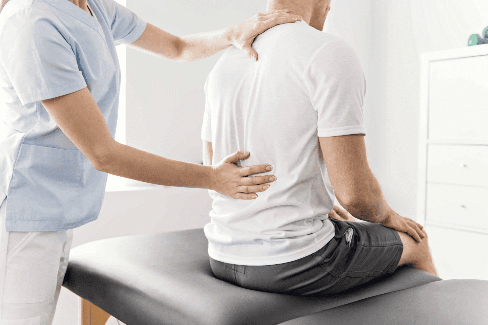 Physical therapist examining a patient's back during a session.