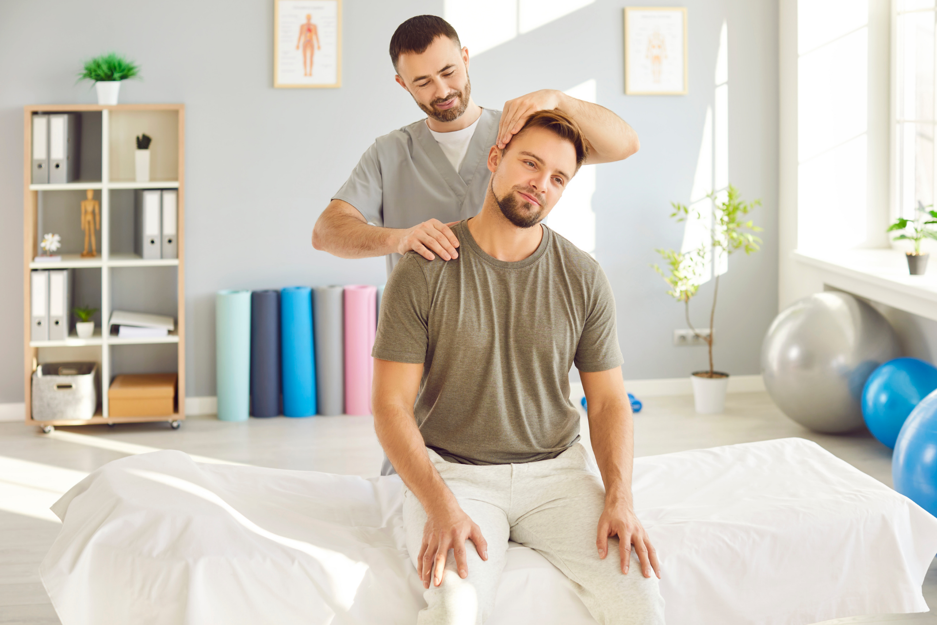 Physical therapist performing a neck adjustment on a seated man in a clinic