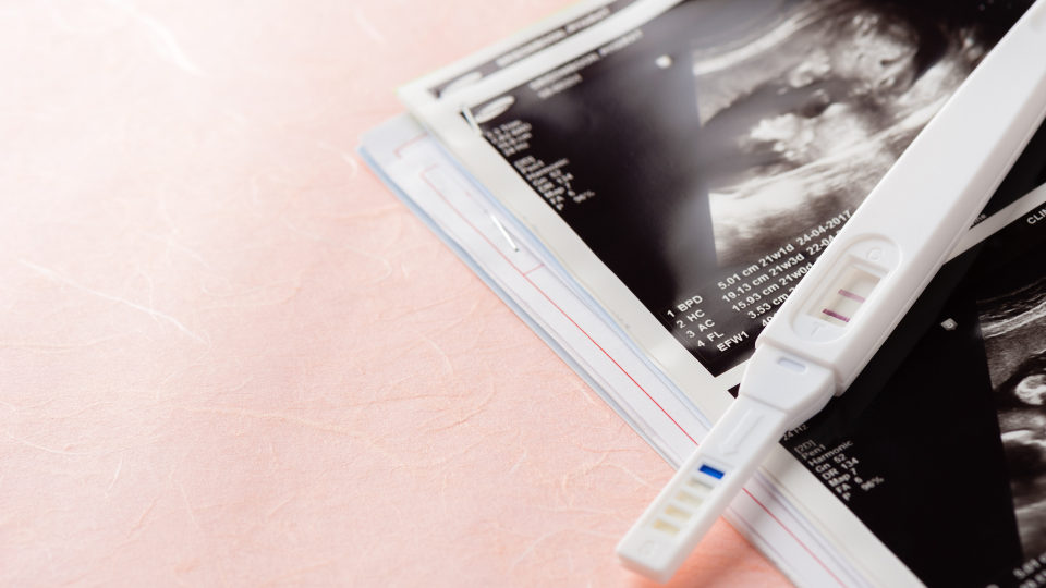 Pregnancy test on top of sonogram images.