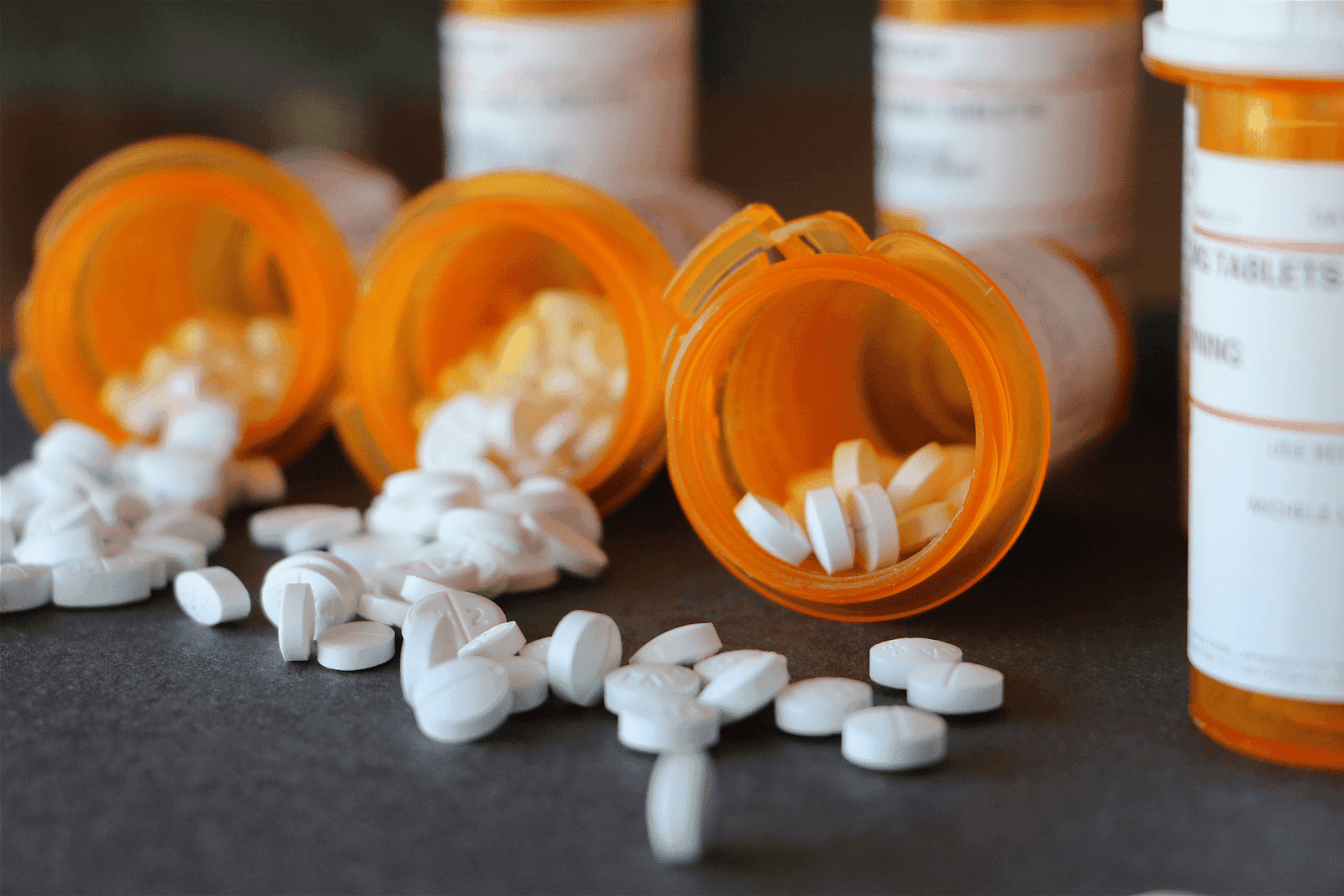 Prescription pill bottles tipped over with white tablets spilling out
