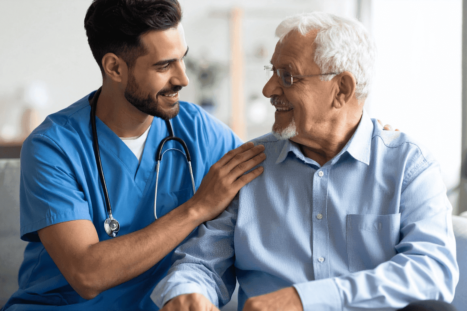 Smiling doctor comforting an older male patient.