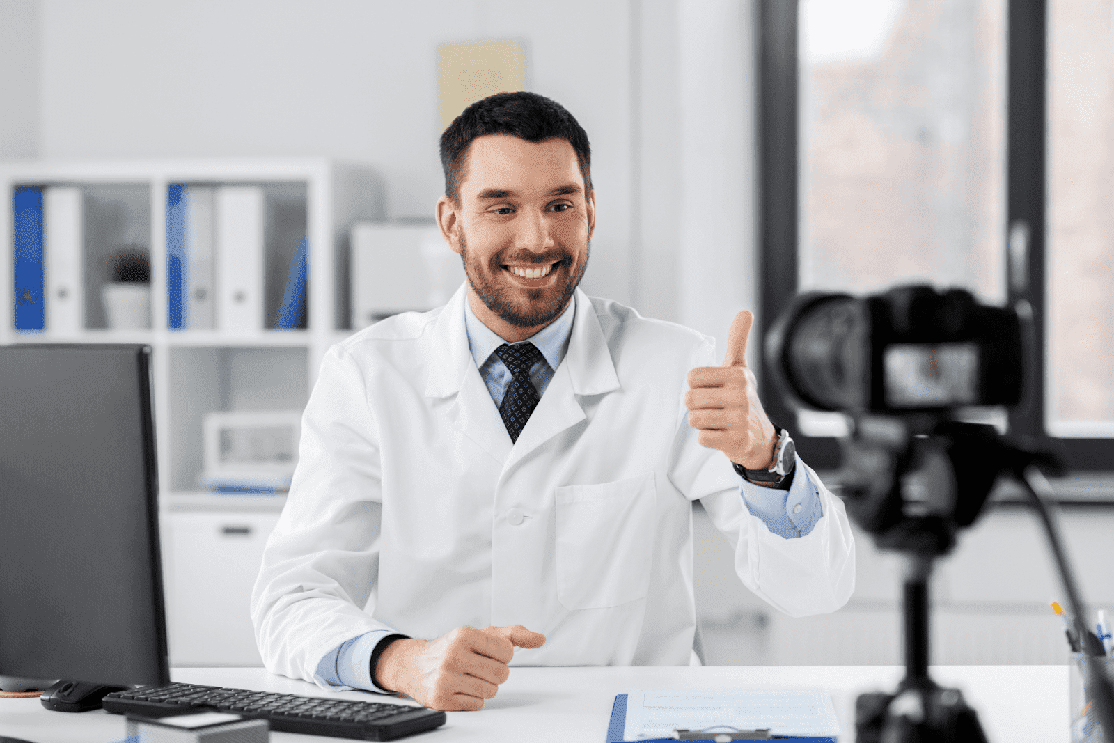 Smiling doctor giving a thumbs-up while recording on camera