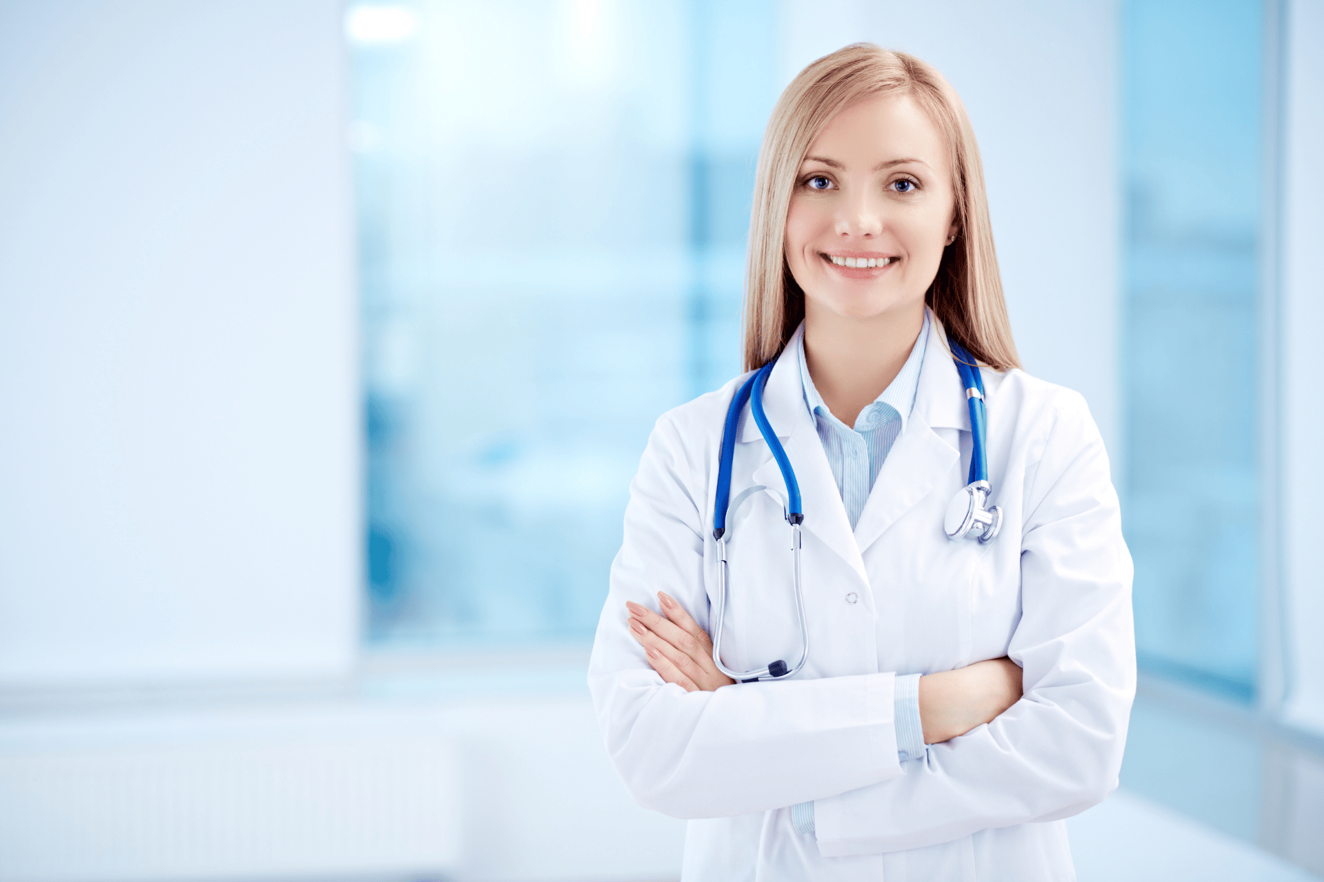 Smiling doctor with a stethoscope standing confidently in a bright medical office.