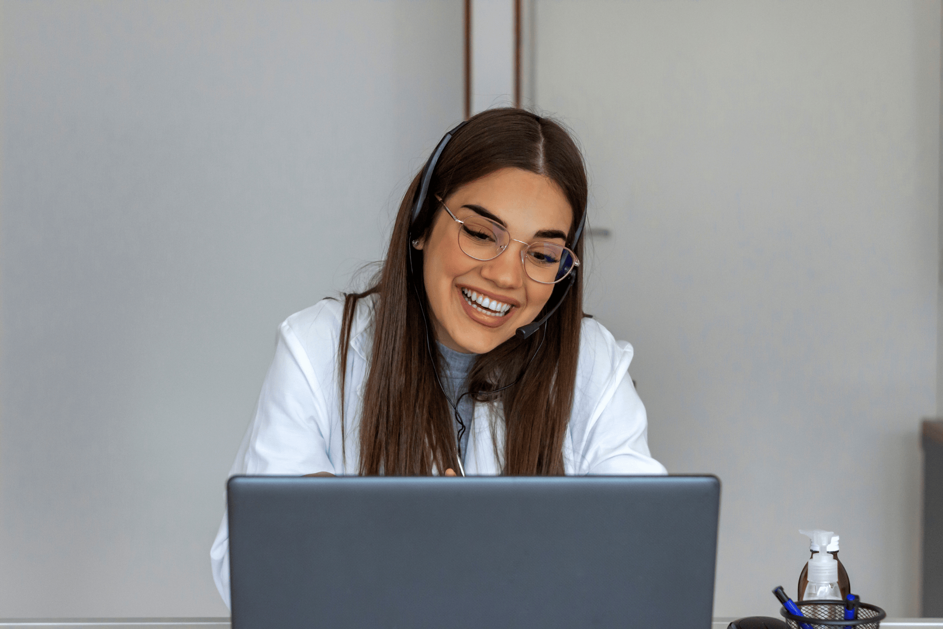 Smiling female doctor wearing a headset during an online consultation.