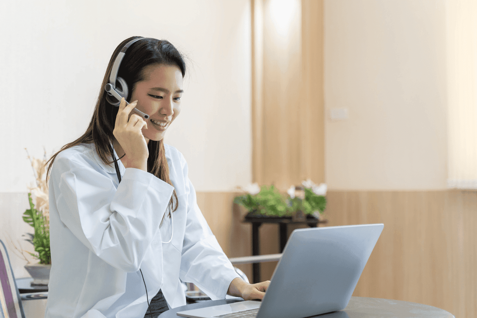 Smiling female doctor wearing a headset while talking on a video call.