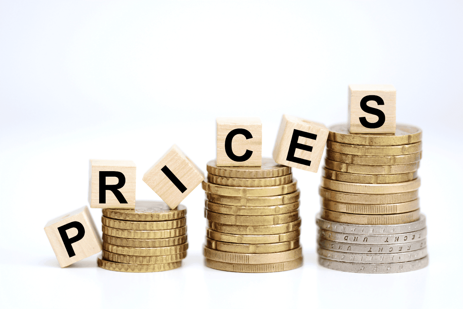 Stacked coins with wooden blocks spelling the word ‘PRICES’.