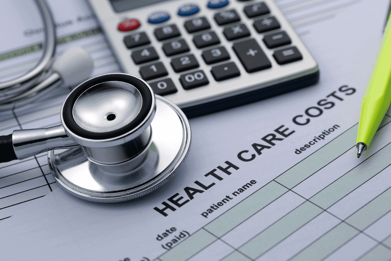 Stethoscope, calculator, and pen on a health care cost form
