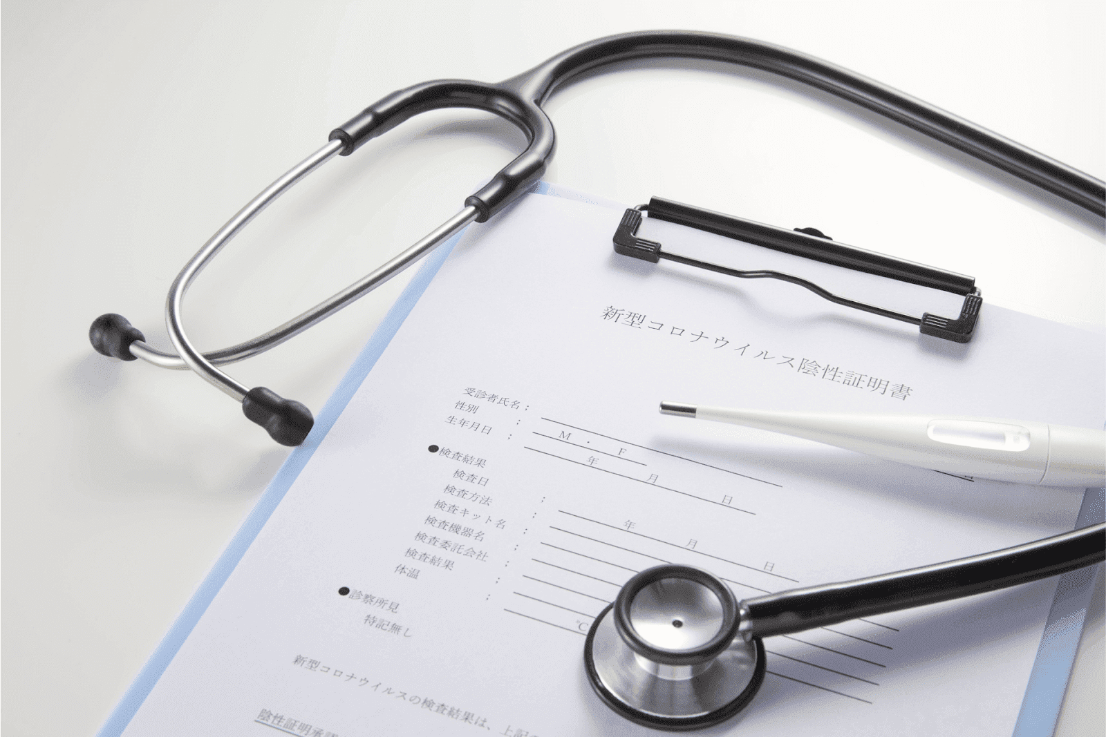 Stethoscope and thermometer placed on a medical form on a clipboard.