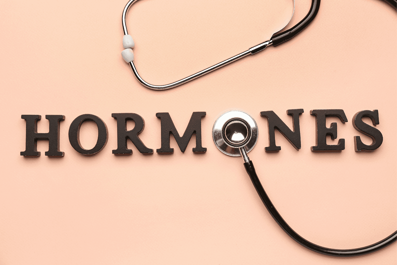 The word 'HORMONES' with a stethoscope on a peach background.