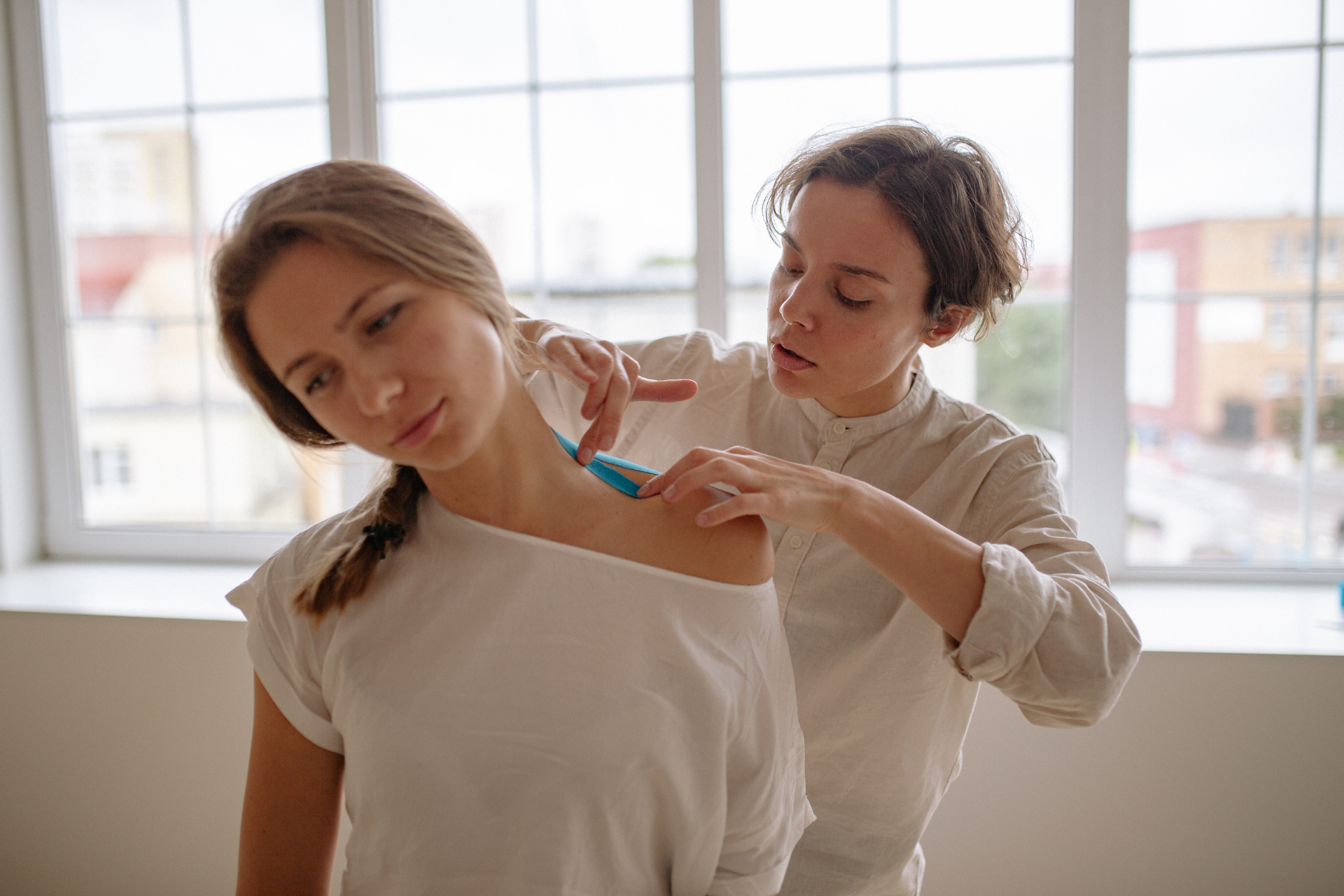Therapist applying kinesiology tape to a woman’s shoulder