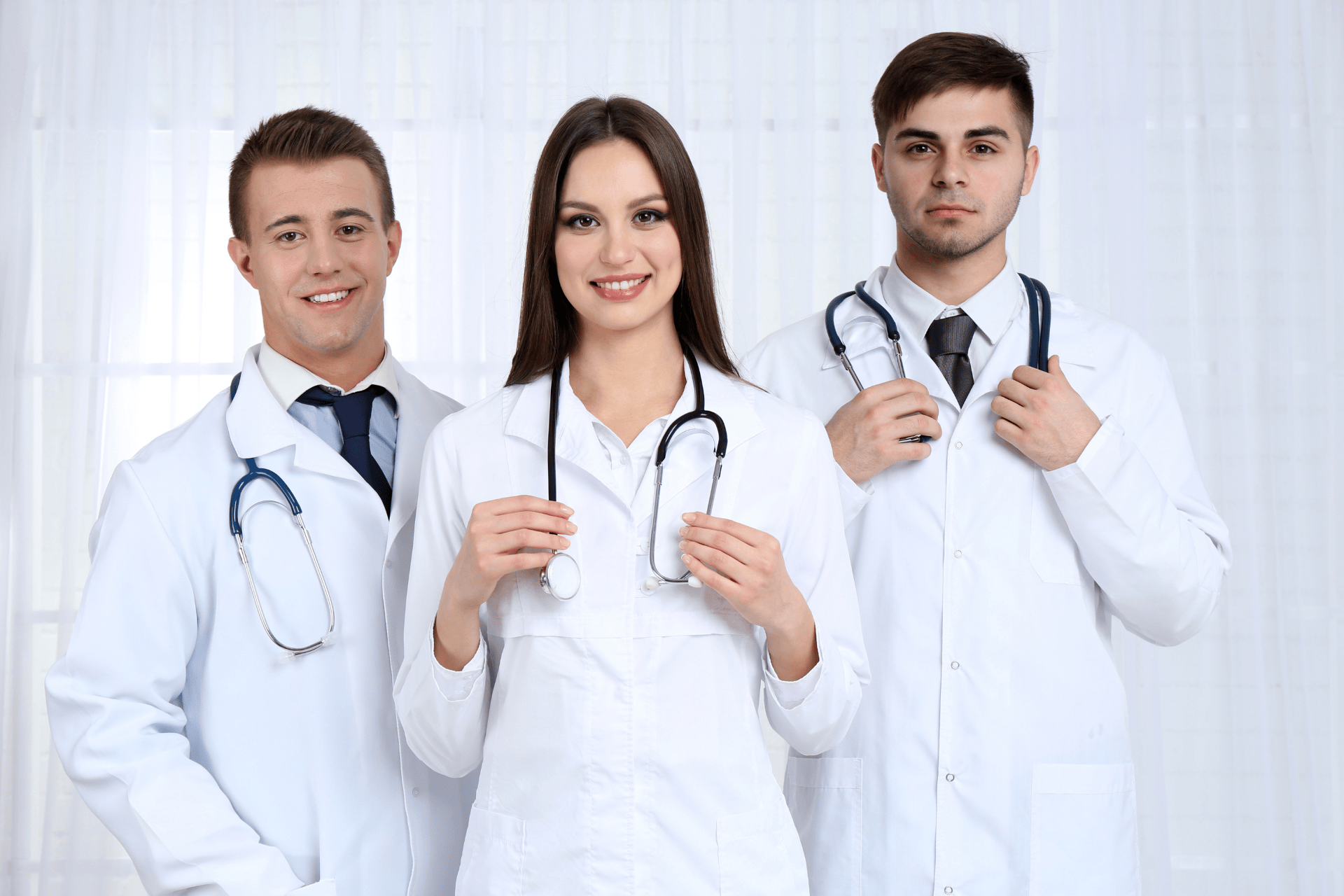 Three doctors in white coats standing together with stethoscopes.
