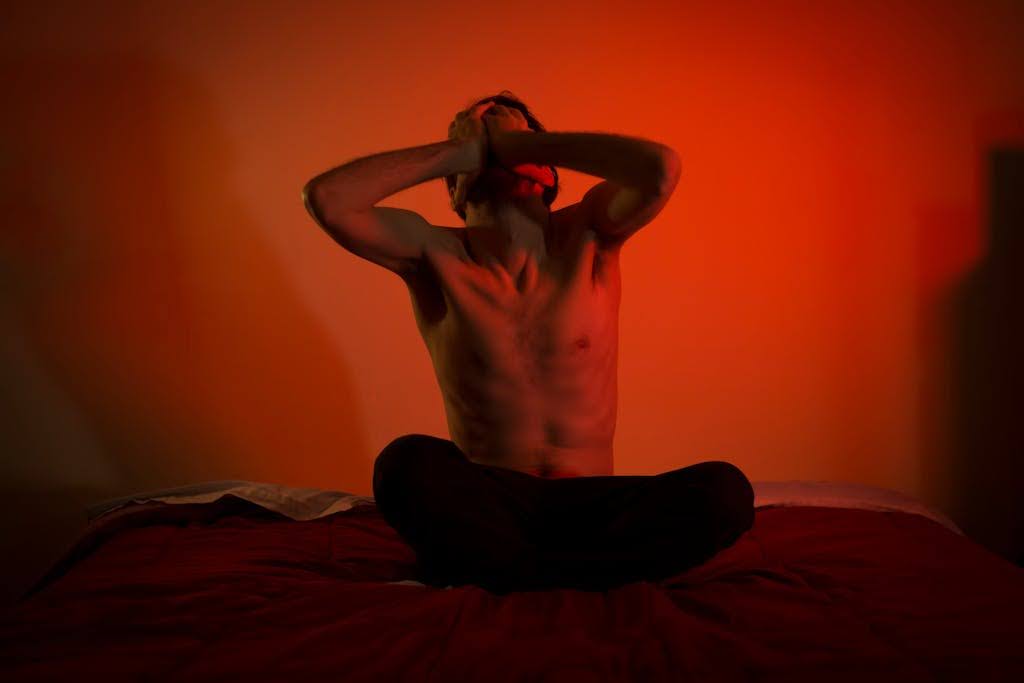 A topless man sitting.