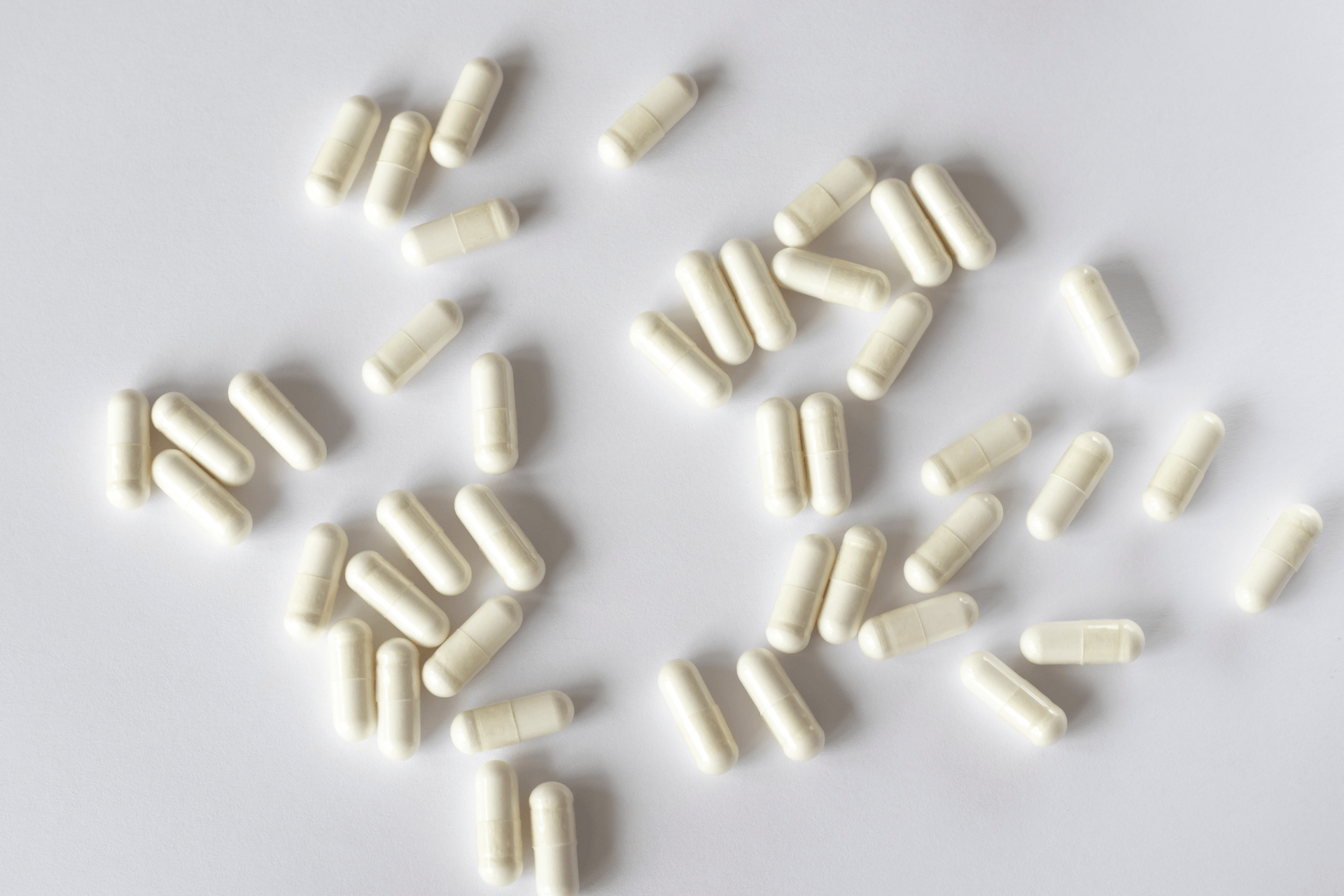 White capsules scattered on a light surface.