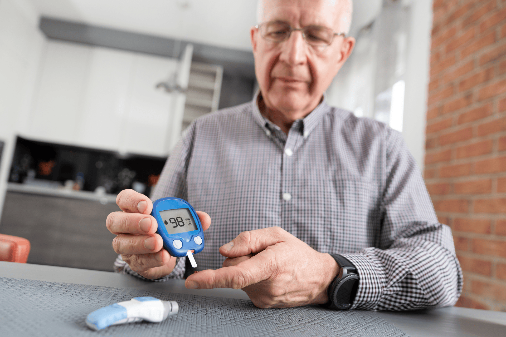 Man using a glucose meter to check his blood sugar level at home.