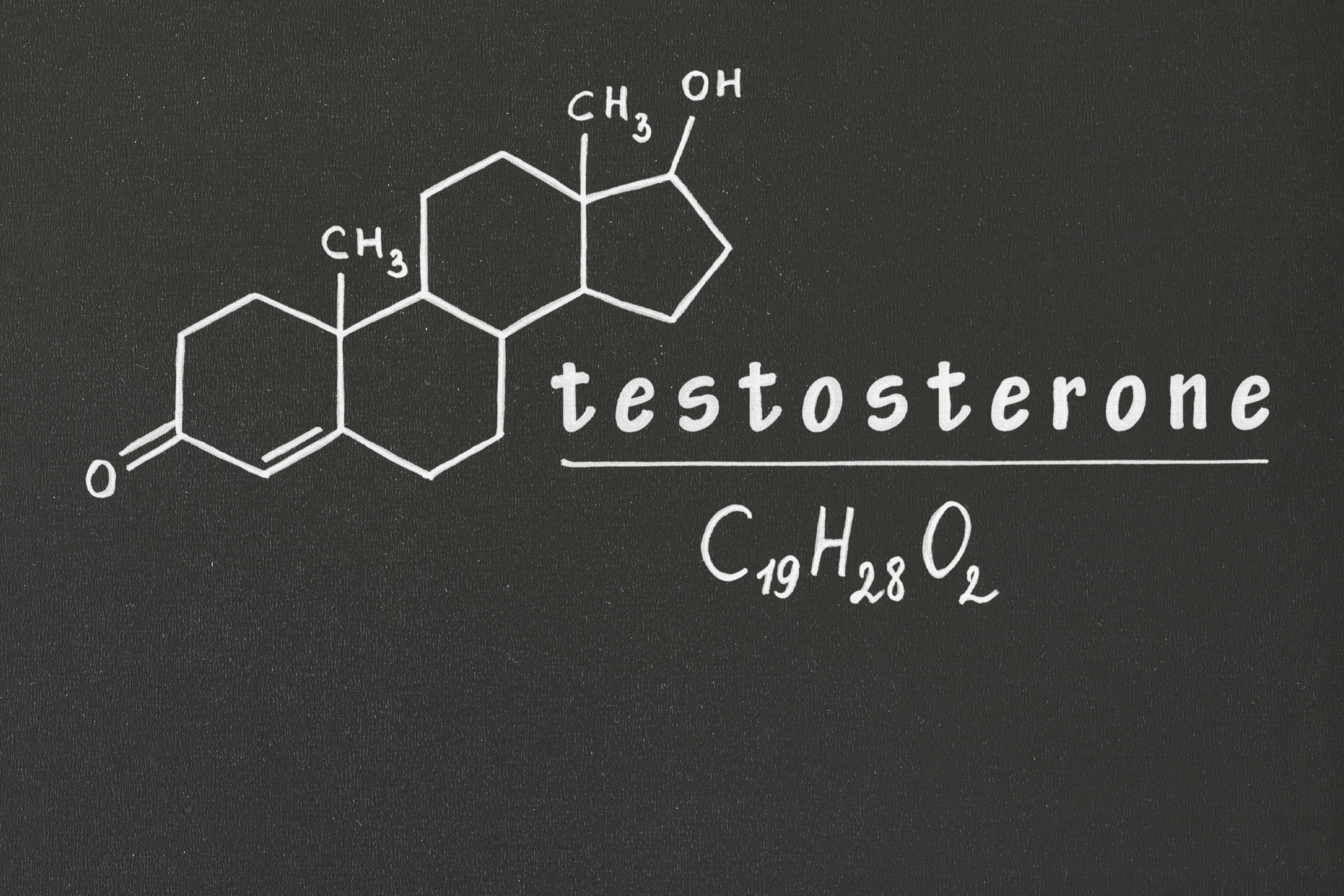 Testosterone chemical structure and formula drawn on a chalkboard.