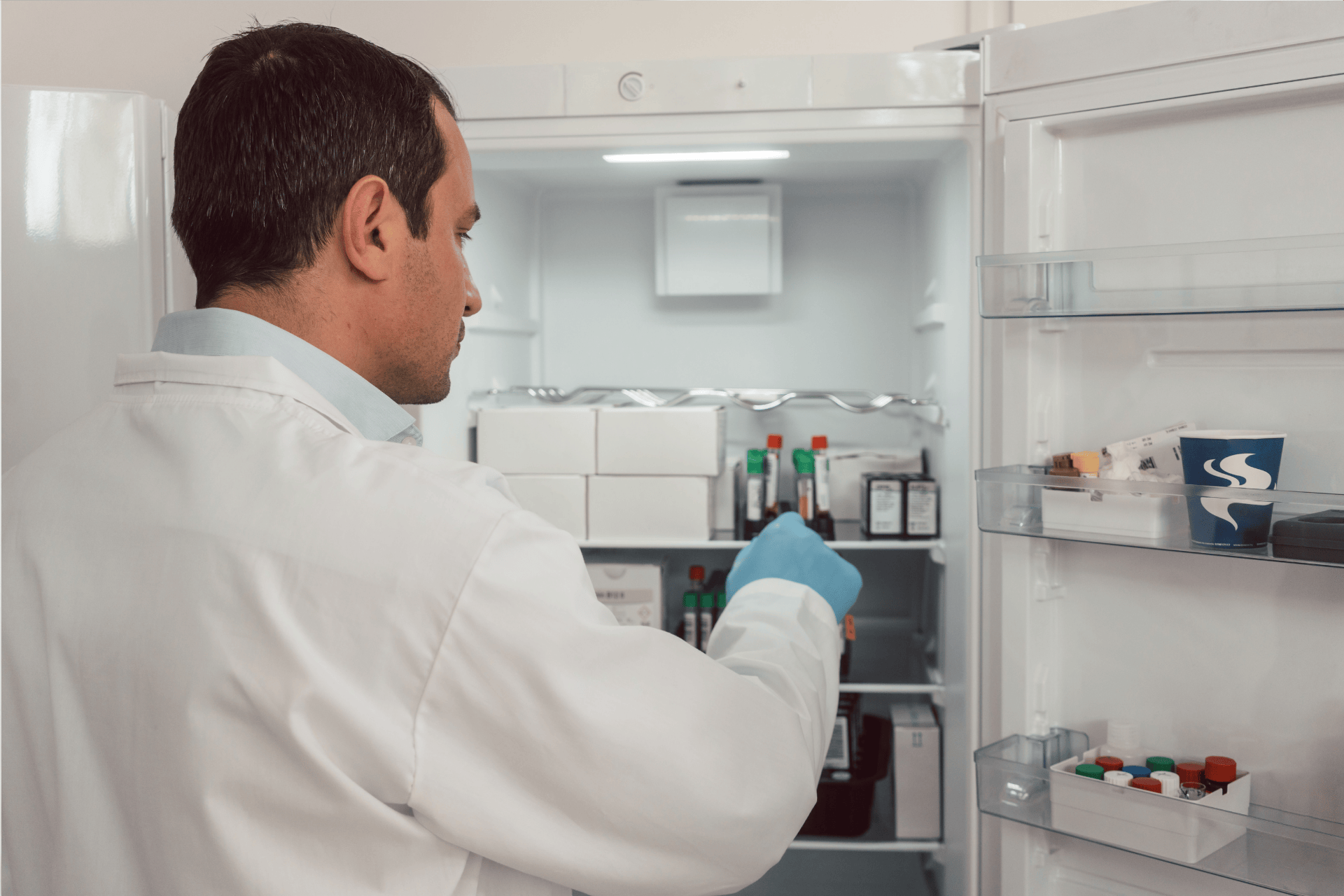 Scientist or doctor taking samples from a medical refrigerator in a lab.