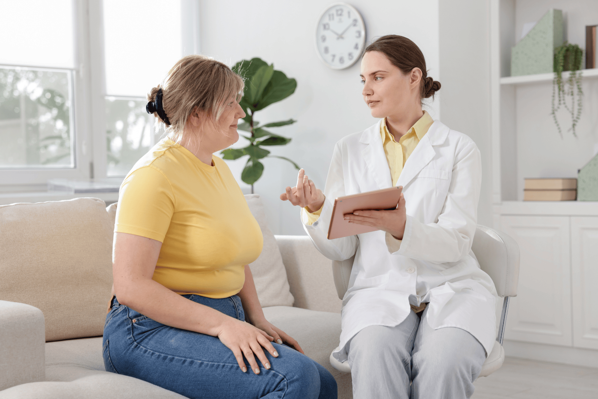 Doctor consulting with a patient while holding a tablet during an appointment.