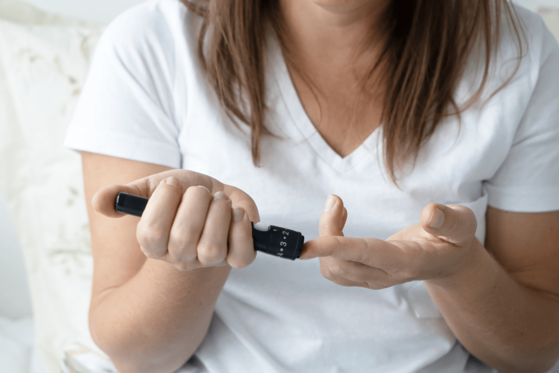 Woman using a lancet device to check blood sugar levels.