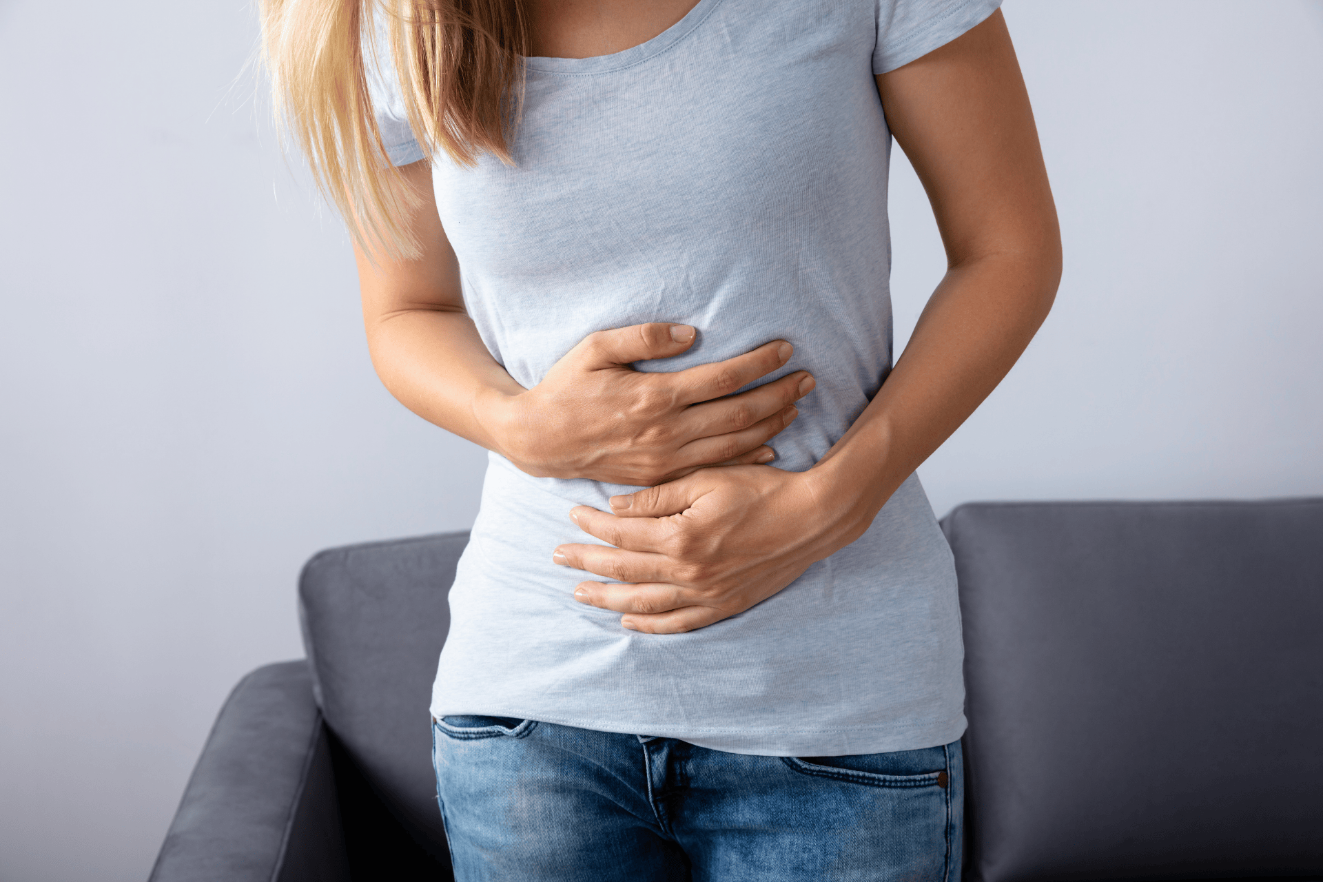 Woman holding her stomach in discomfort, possibly experiencing abdominal pain.