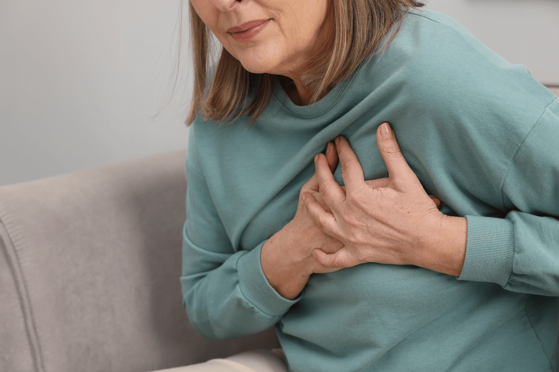 Older woman clutching her chest in discomfort.