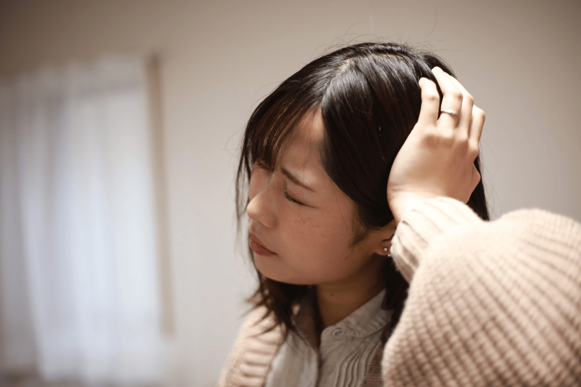 Woman touching her head and appearing to be in pain or discomfort.