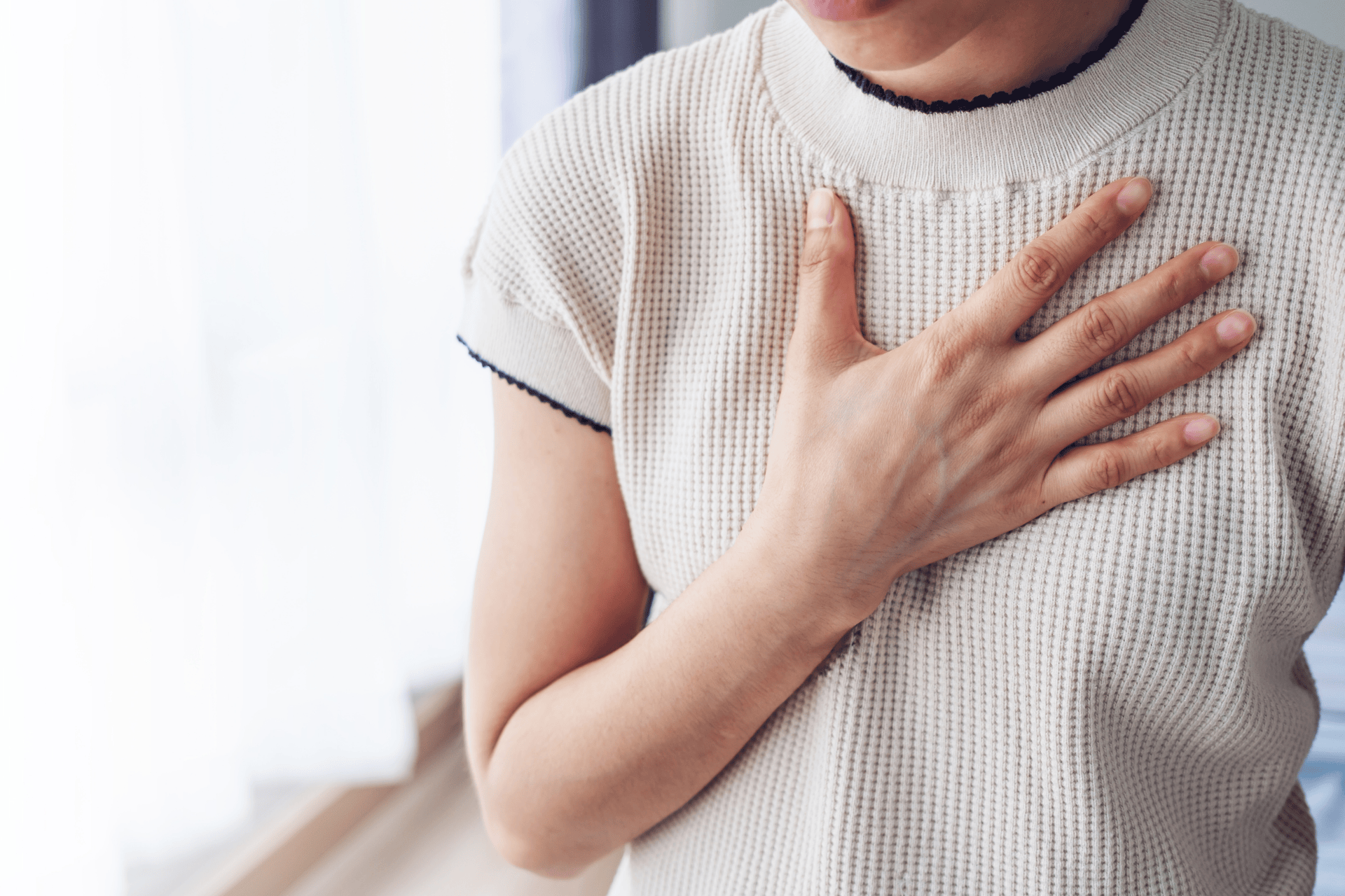 Woman touching her chest, appearing to experience discomfort or pain.