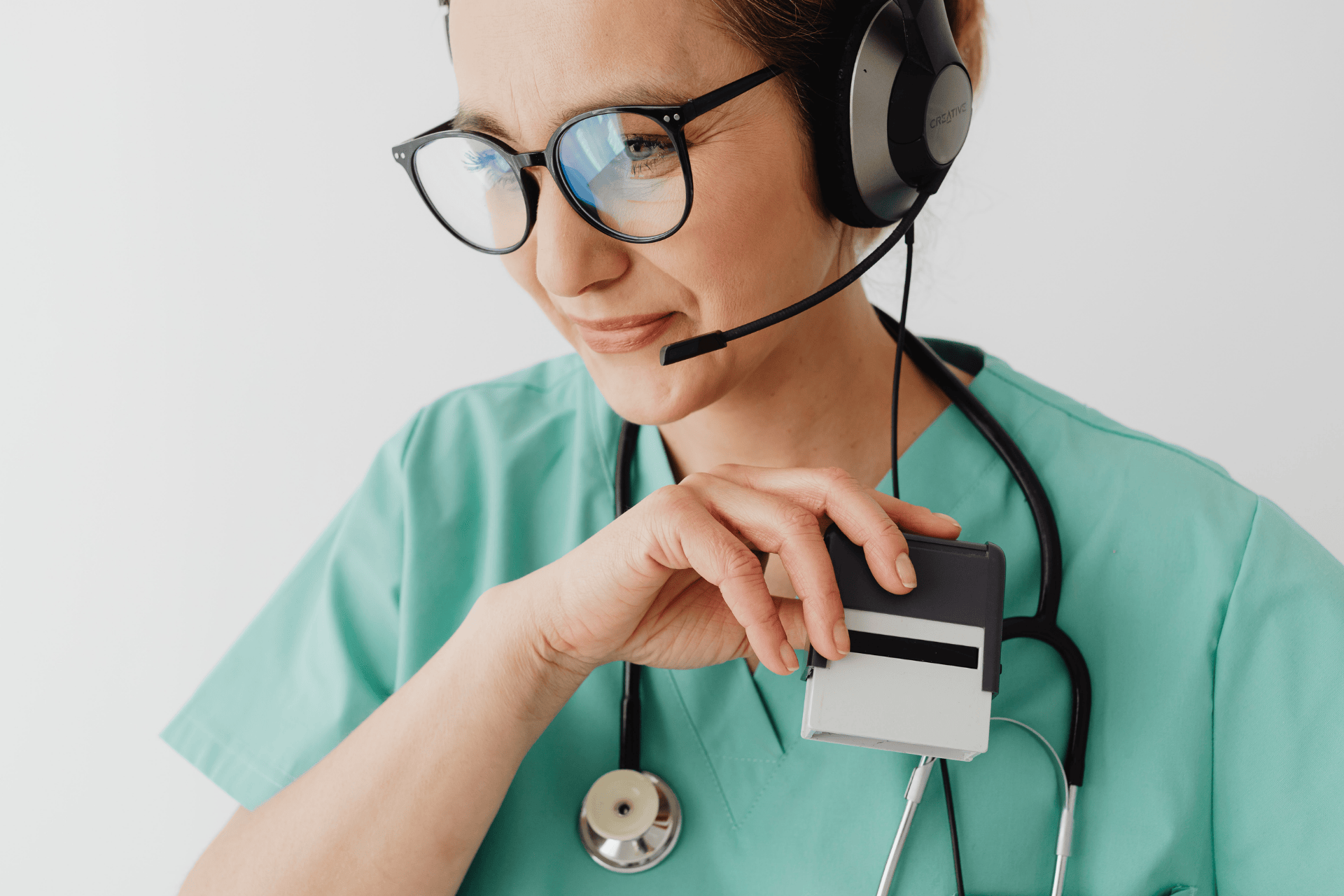 Female healthcare professional wearing scrubs and headset, holding an ID card.