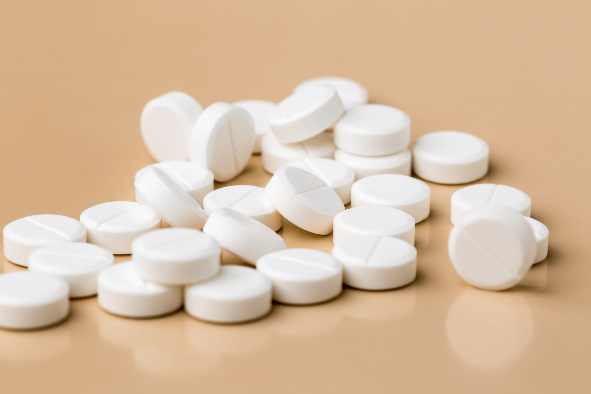 White round tablets scattered on a beige surface.