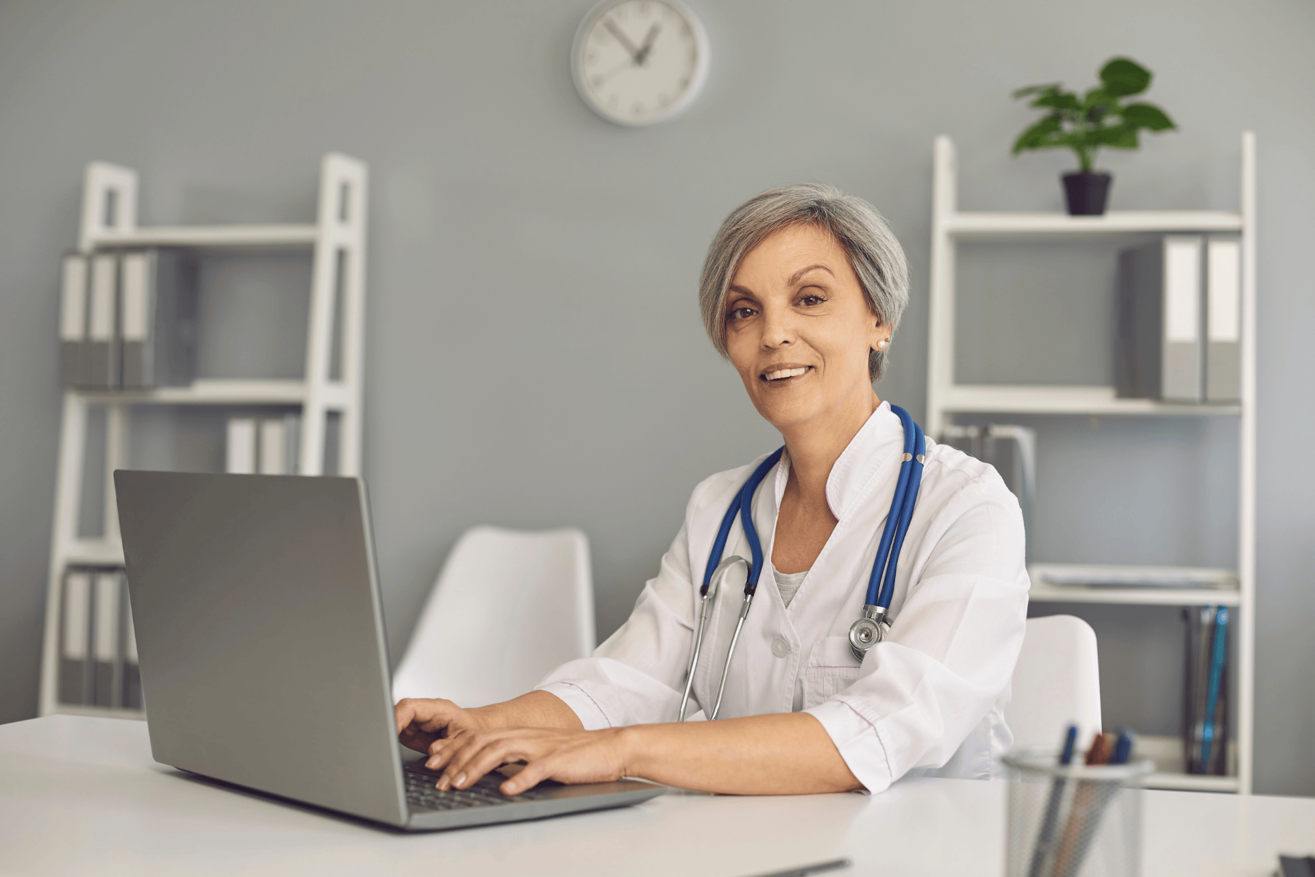 Smiling female doctor working on a laptop at her desk.