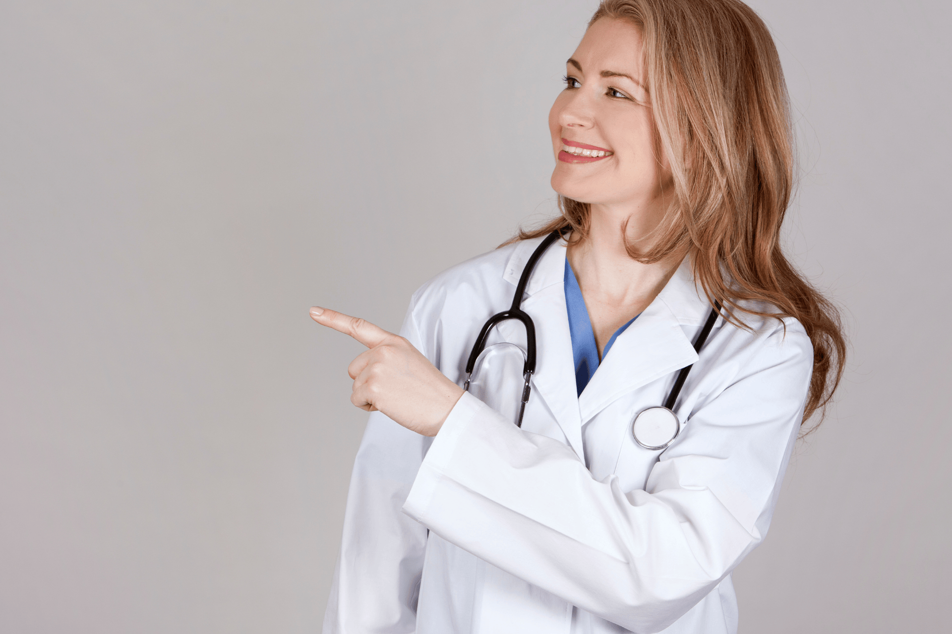 Female doctor smiling and pointing to the side.