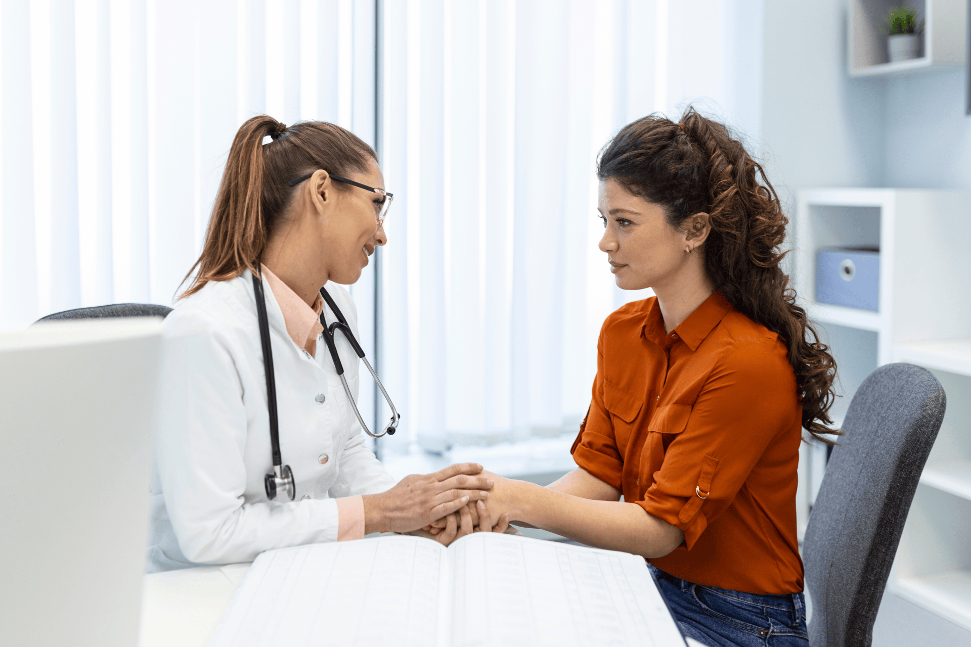 Doctor comforting a patient during a consultation in a medical office.