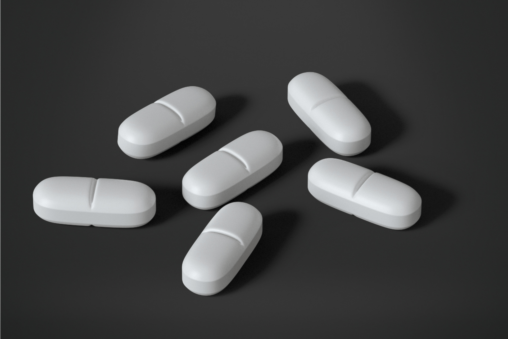 Several white oblong tablets arranged on a dark surface