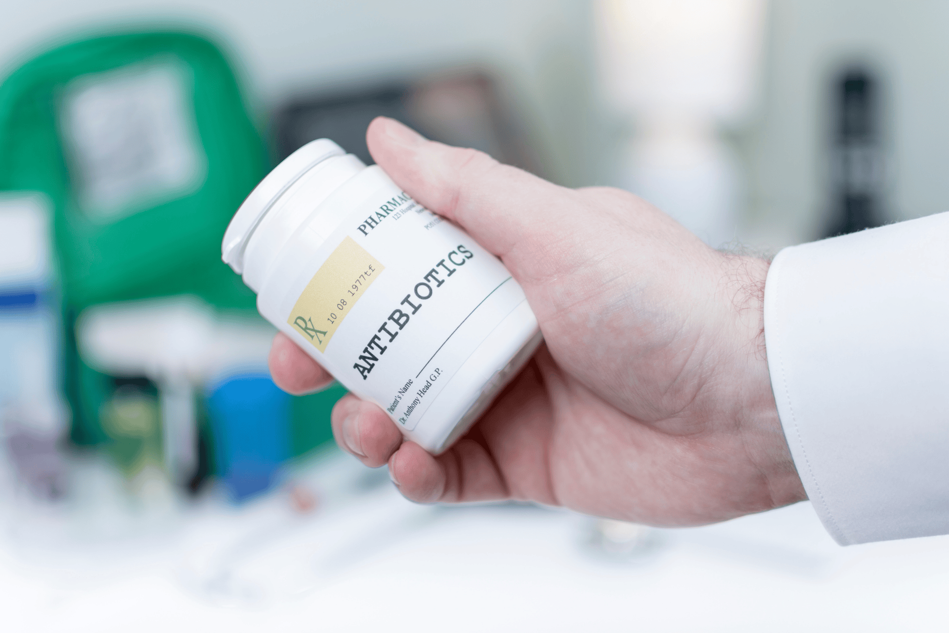 Hand holding a prescription bottle labeled antibiotics