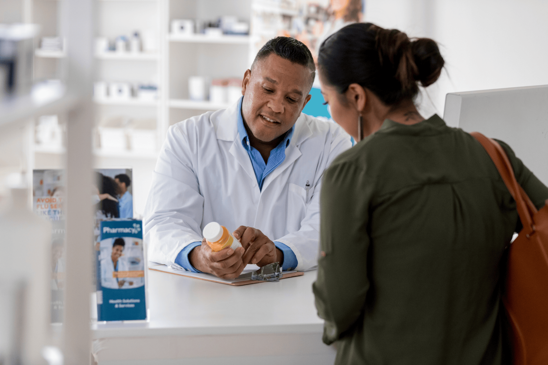 Pharmacist explaining a prescription bottle to a woman at the counter