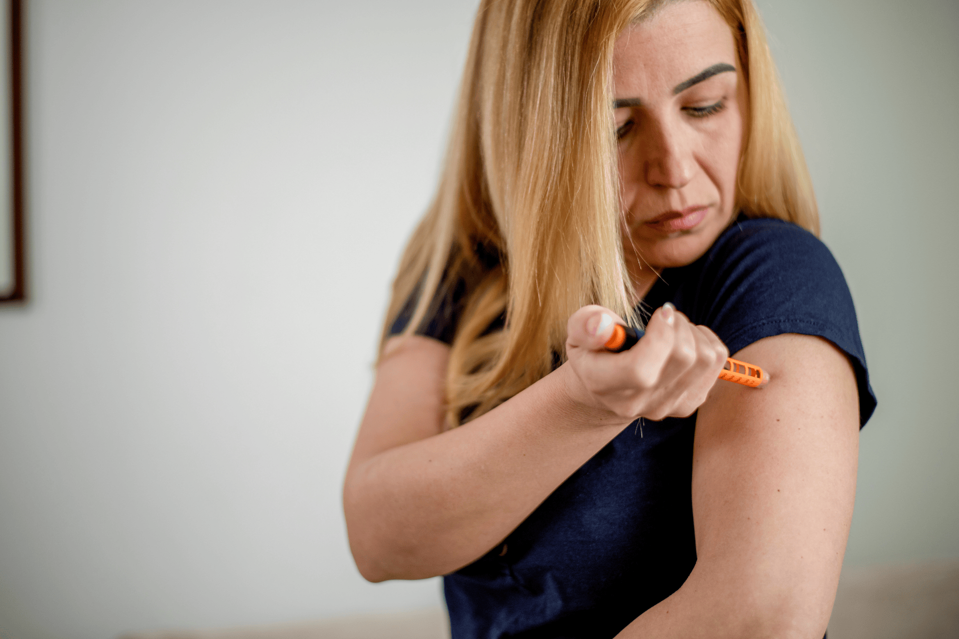Woman injecting her upper arm with an insulin pen at home.