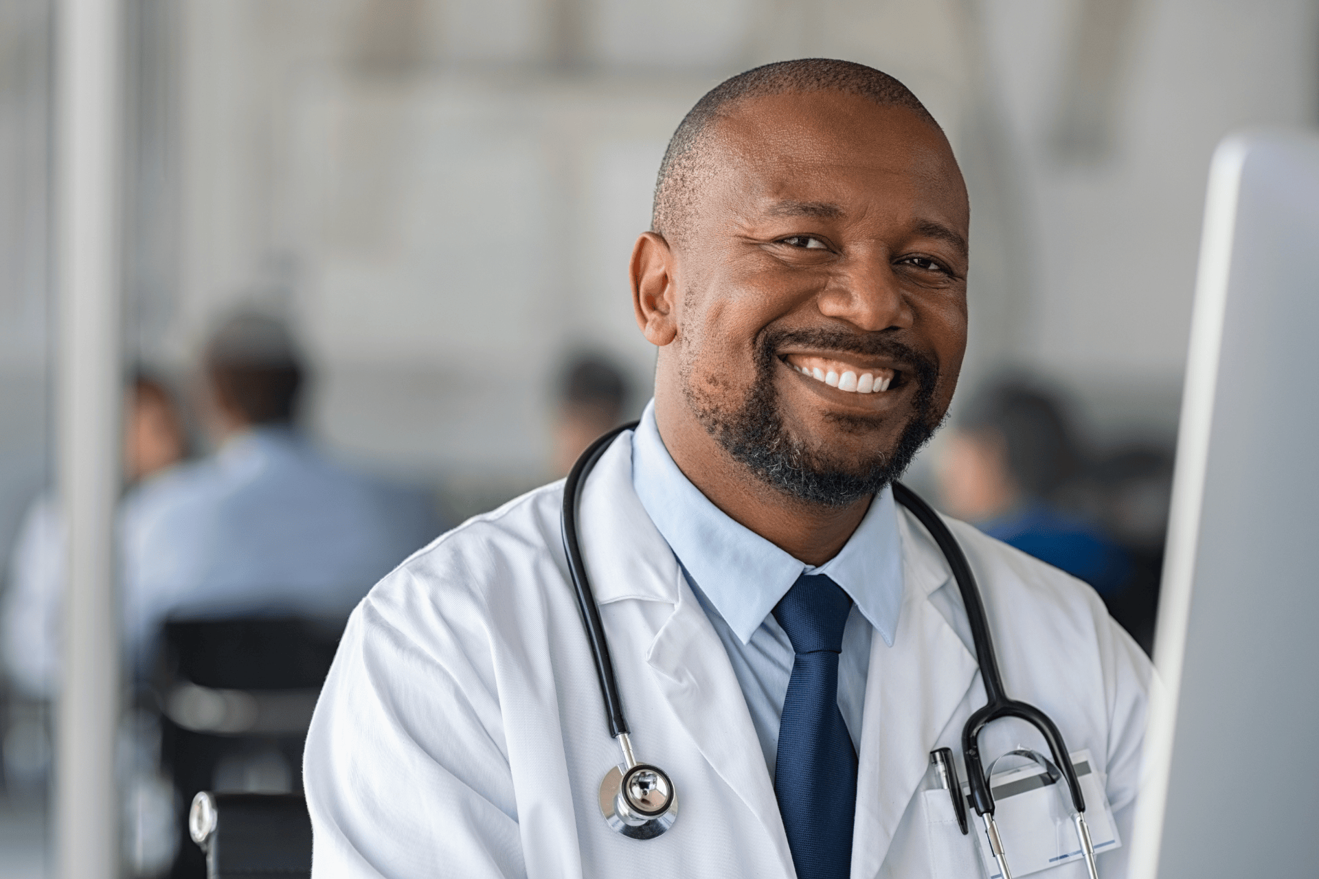 Smiling doctor wearing a white coat and a stethoscope.