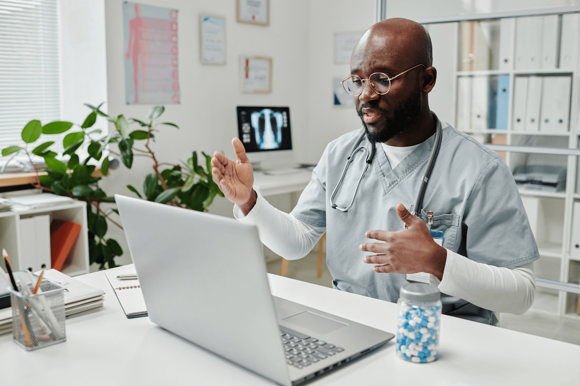 Doctor talking and gesturing during a video call on his laptop.