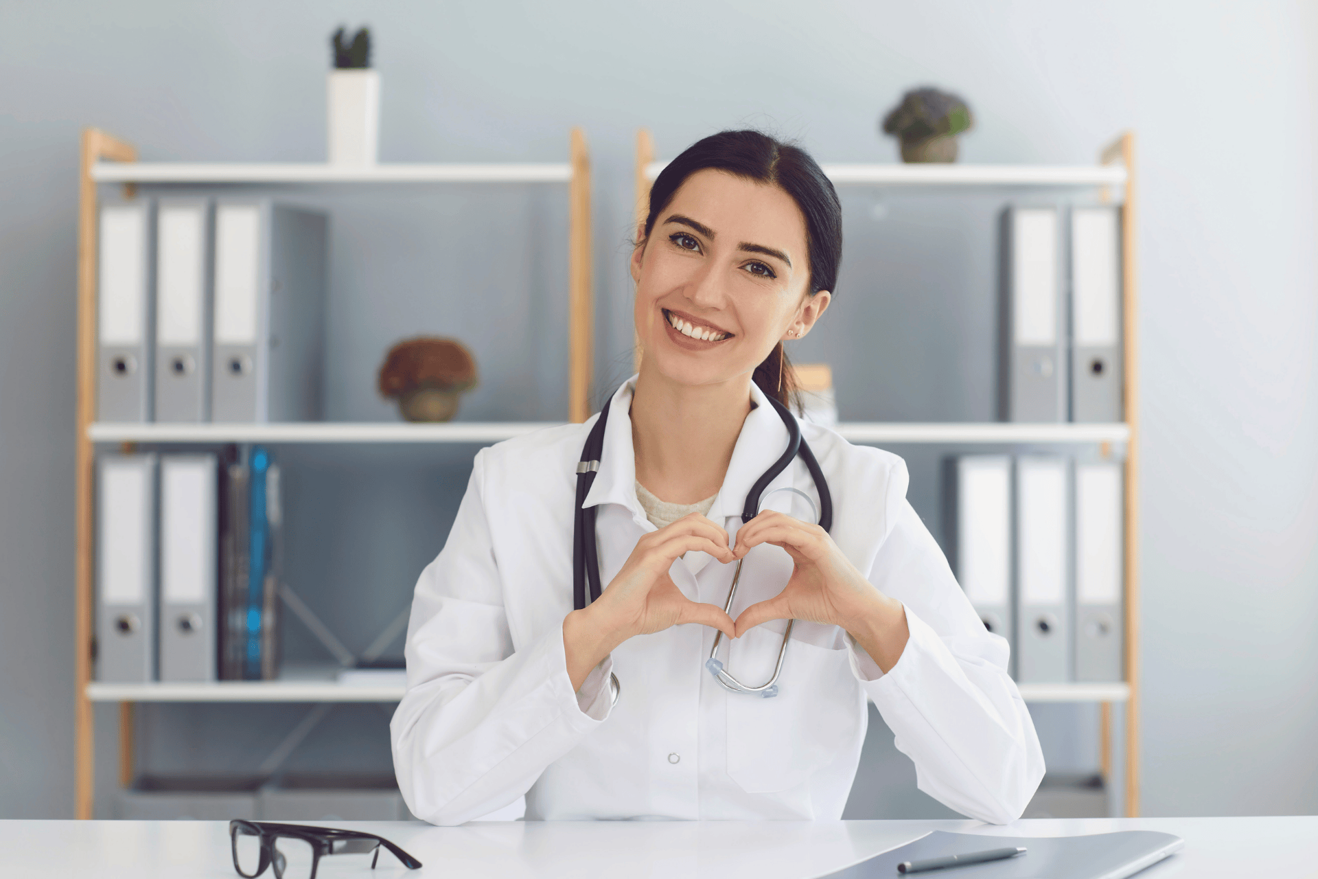 Smiling female doctor forming a heart shape with her hands.