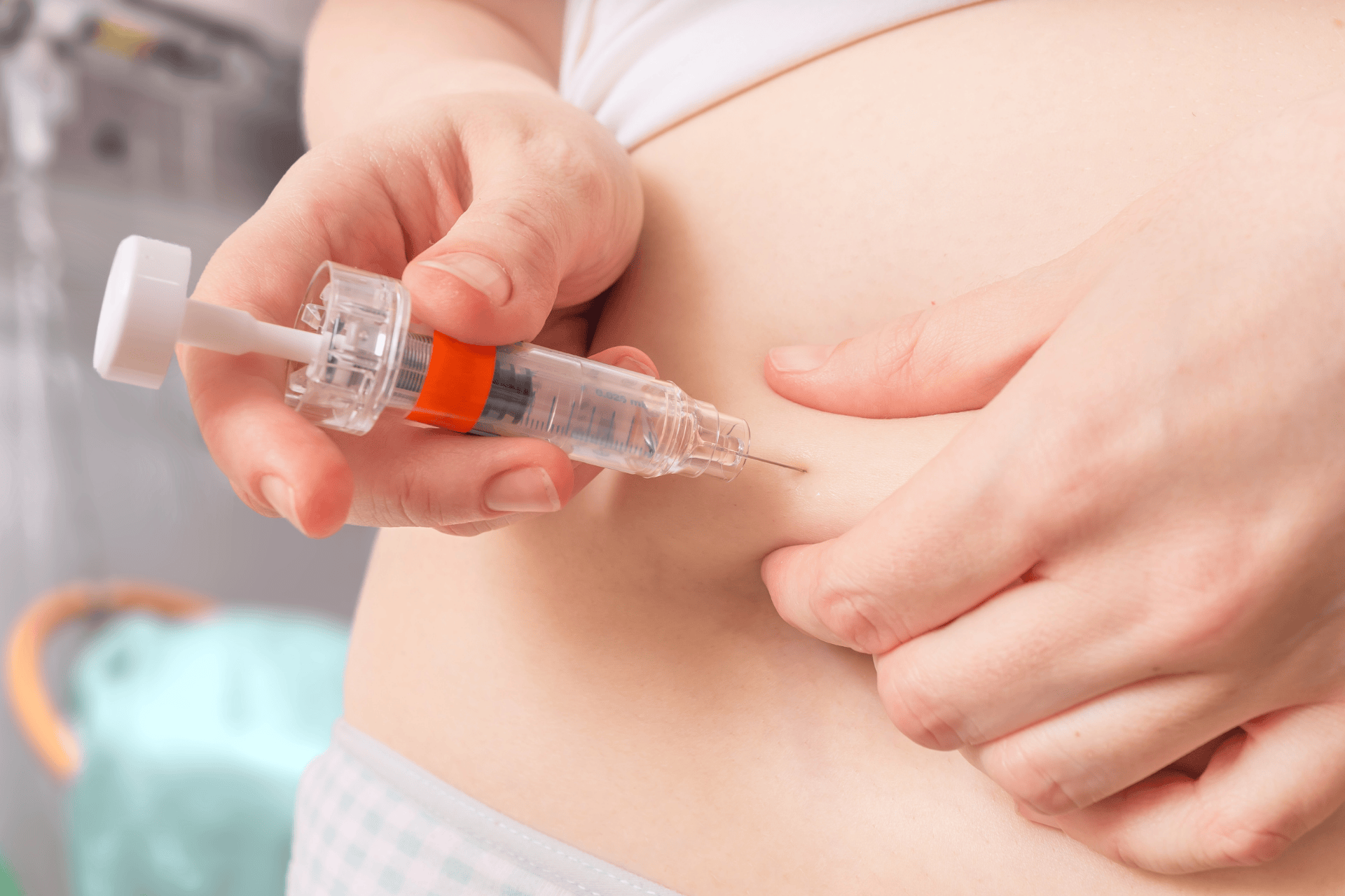 Close-up of a person injecting medication into their abdomen with a syringe.