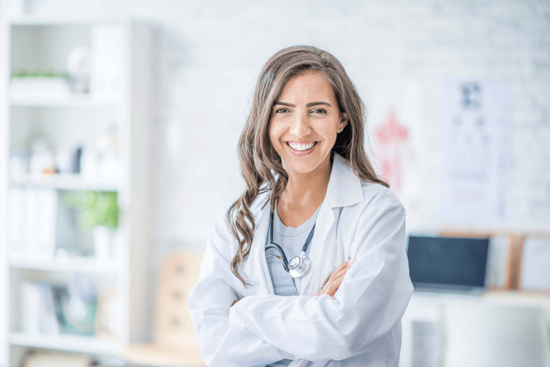 Smiling female doctor in a white coat with arms crossed.