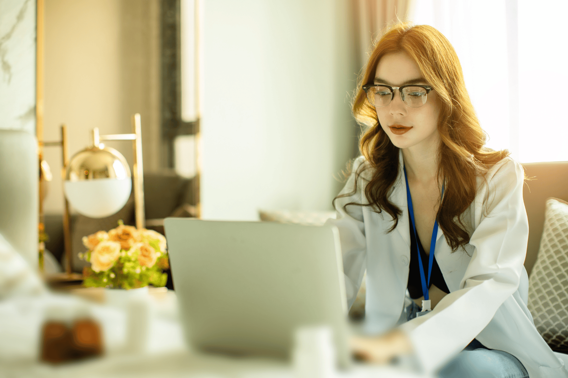 Female doctor in a white coat working on a laptop.